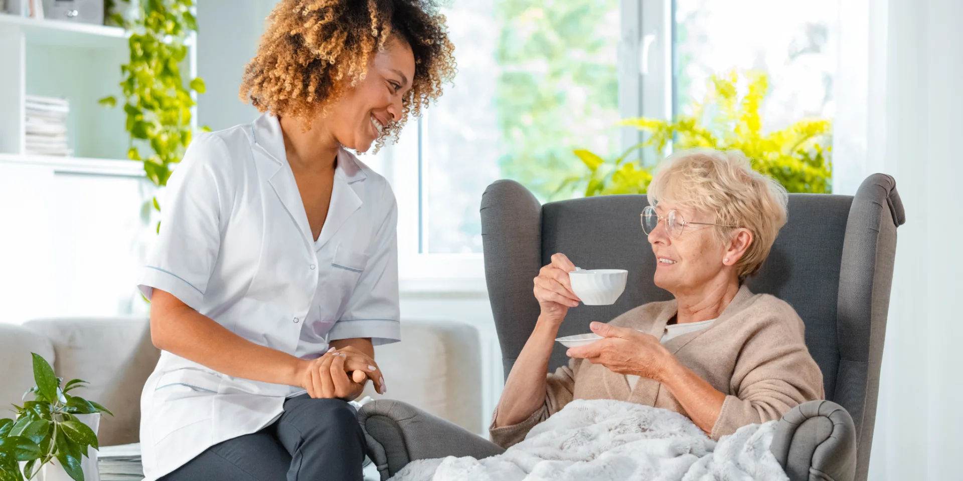 Pflegekraft und Seniorin bei einer Tasse Tee zuhause – Delme-Care, ambulanter Pflegedienst in Delmenhorst