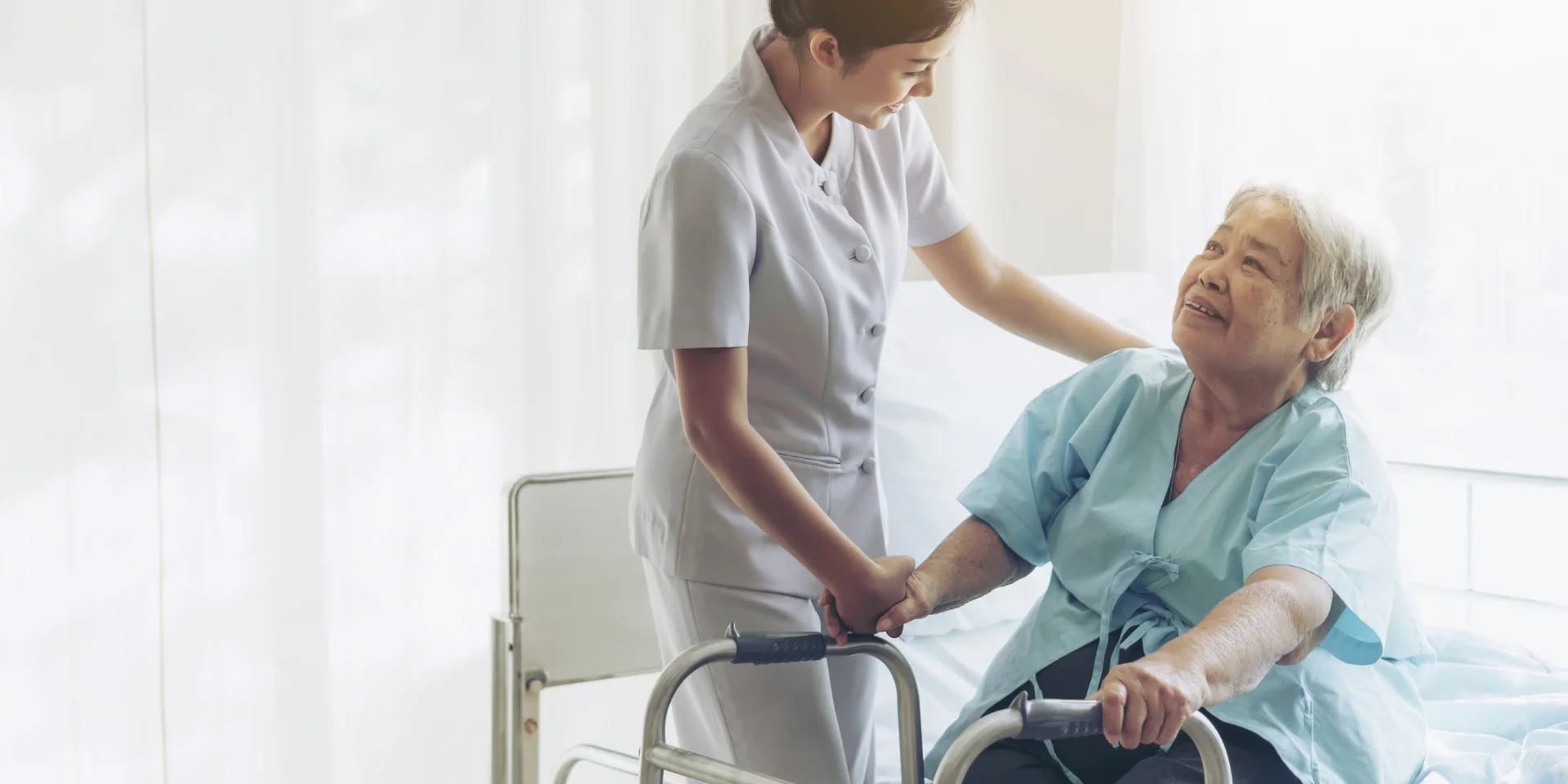 Pflegekraft hilft einer Seniorin beim Aufstehen aus dem Bett – Delme-Care, ambulanter Pflegedienst in Delmenhorst